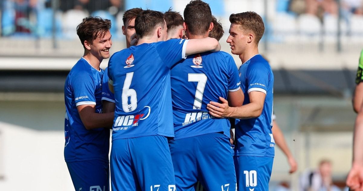 Eine Fußballmannschaft feiert ein Tor mit Spielern in blauen Trikots mit den Nummern 6, 7, 10 und 17.