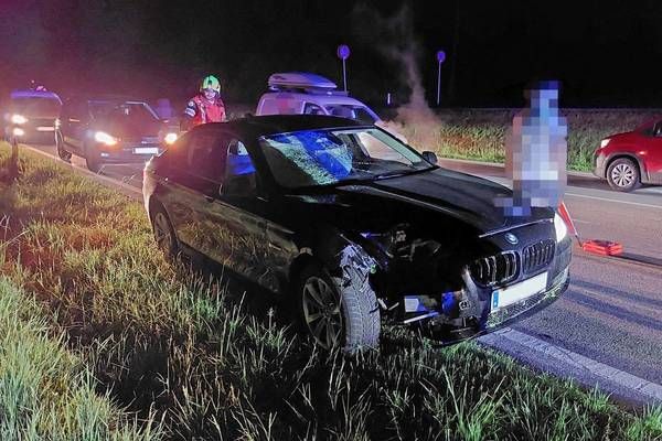 Ein schwarzer BMW ist auf der Straße kaputt, mit Rettungsfahrzeugen und Personal darum herum.