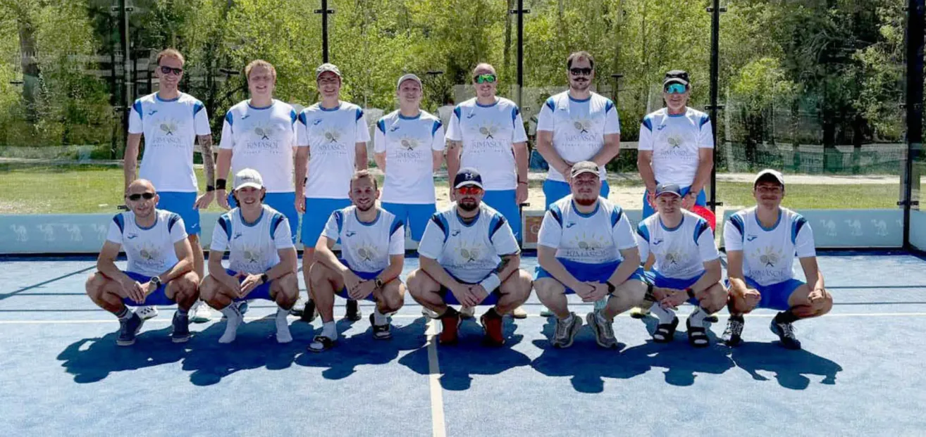 Eine Gruppe von Männern in einheitlichen Outfits posiert für ein Foto auf einem Tennisplatz.