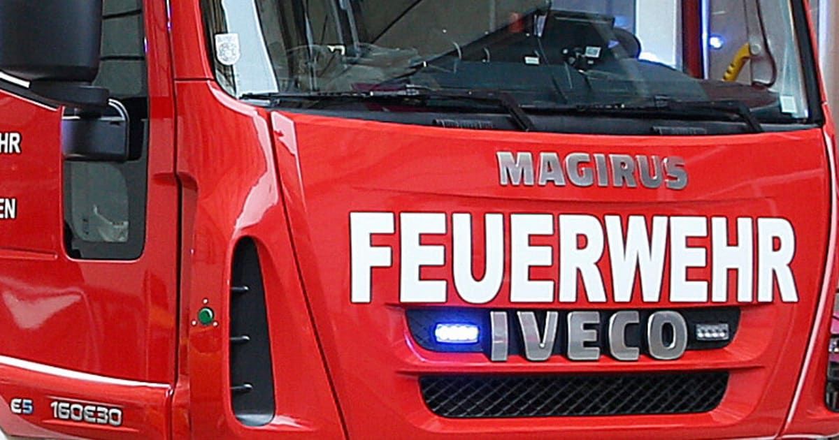 Ein roter Magirus Feuerwehrwagen mit weißen Buchstaben, die 'FEUERWEHR IVECO' und ein blaues Licht auf der Stoßstange lesen.