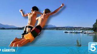 Zwei Jungen springen in einen klaren blauen See mit Bergen im Hintergrund. Sie zeigen auf etwas.