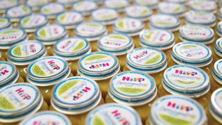 Nahaufnahme von vielen Gläsern Hipp Babynahrung mit bunten Etiketten. Die Gläser sind mit gelbem Essen gefüllt und die Etiketten haben das Wort 'HiPP' deutlich sichtbar.