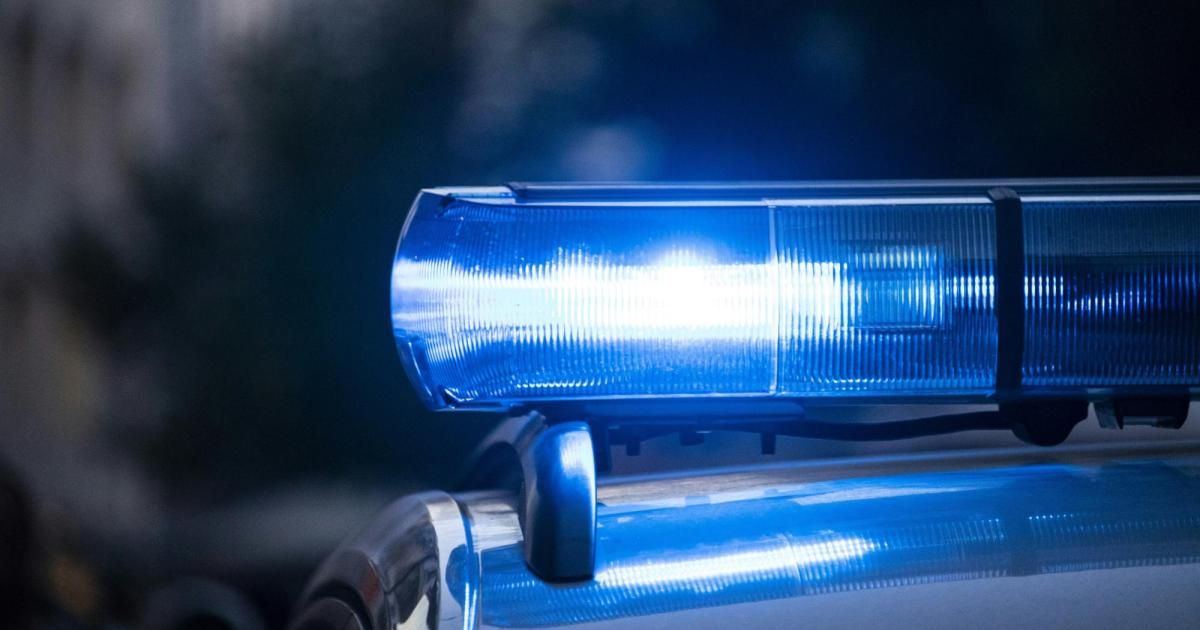 Das blaue Licht einer Polizeiautos erhellt die Nacht und signalisiert einen Notfalleinsatz. Der Schein des Lichts reflektiert sich auf der Fahrzeugoberfläche.