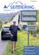 Ein Mann steht neben einem Schild der Semmering Klima-Allianz in der Nähe eines Autos mit dem Nummernschild VB 748. Im Hintergrund ist eine malerische Straße mit einem Bergpanorama zu sehen.