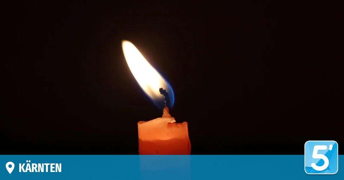 Eine Kerze mit einer blauen Flamme brennt hell vor einem dunklen Hintergrund und wirft ein warmes Licht.