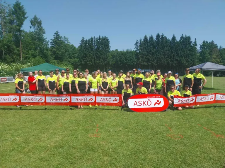 Eine Gruppe von Menschen in passenden gelben und schwarzen Uniformen steht auf einem grünen Feld und posiert für ein Foto mit Bannern.