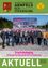 Eine Gruppe von Menschen steht vor einer Baustelle mit einem Werbeschild für das neue Geschäftsgebäude von Elektro Lang. Sie alle lächeln und scheinen für ein Foto zu posieren.