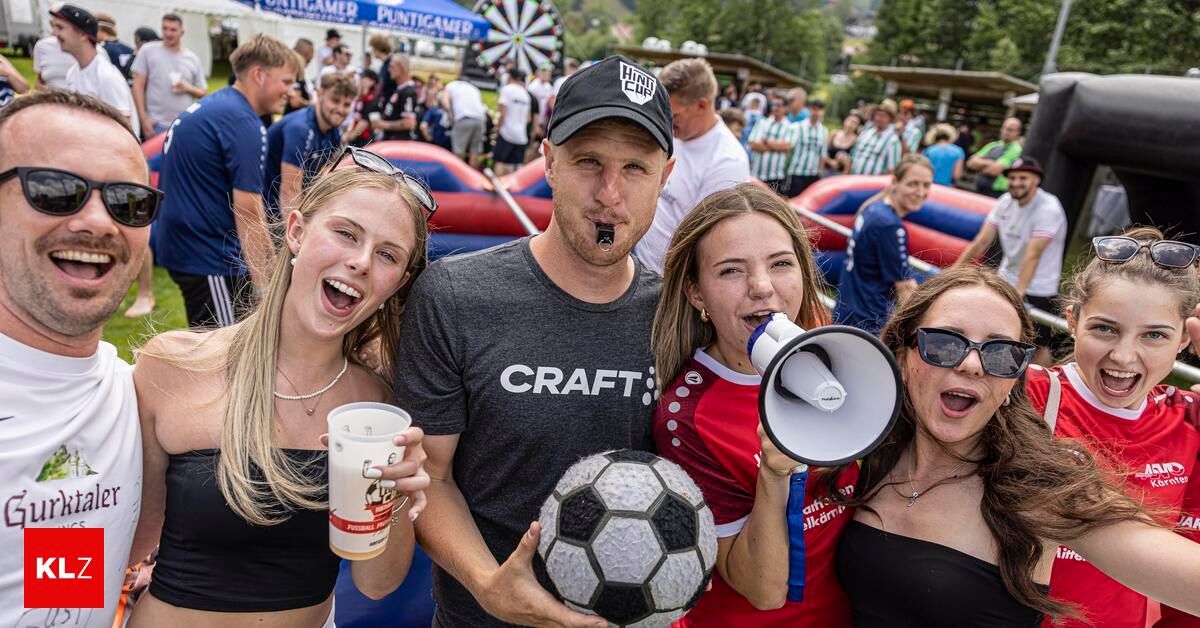 A group of friends, including a man wearing a Craft shirt, are posing with a soccer ball and a cup at an outdoor event.