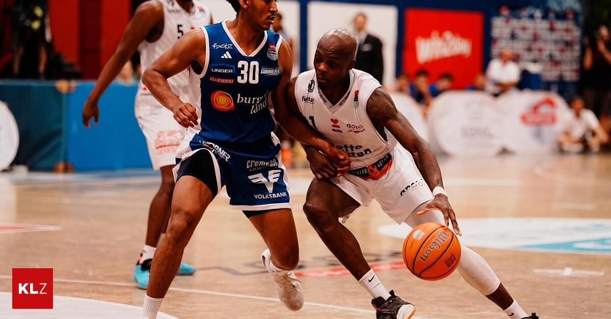 Two basketball players in action on the court. One wearing blue and white, the other in white and red jerseys. The player in white is dribbling the ball.