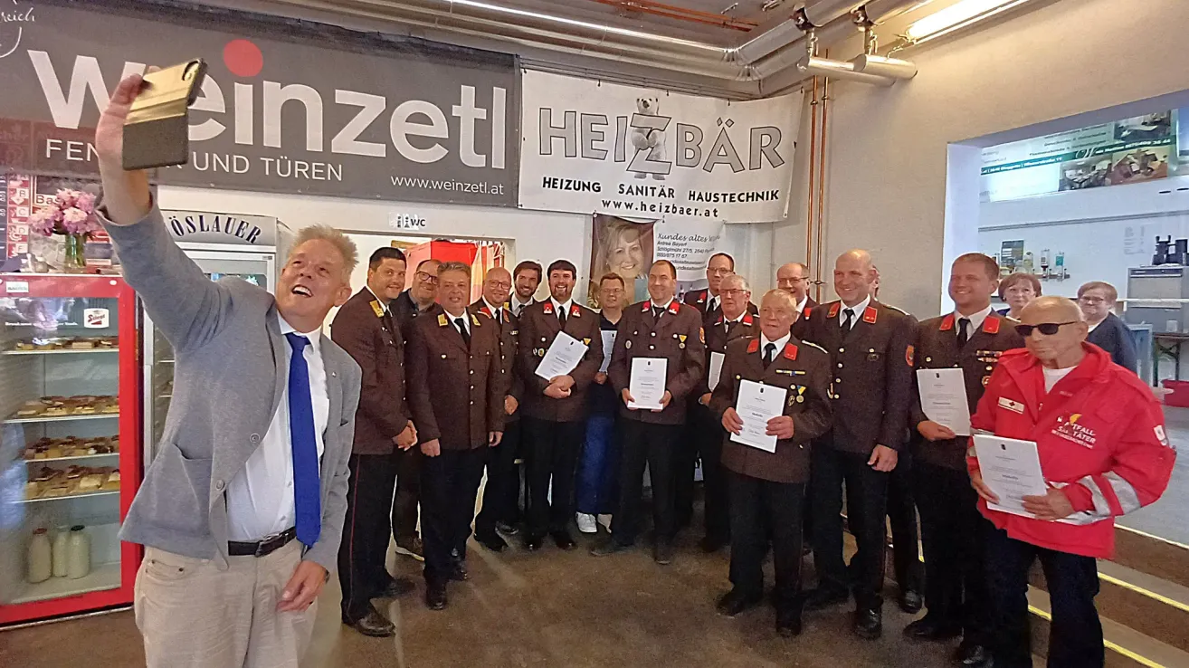 Eine Gruppe von Männern in braunen Uniformen posiert mit Zertifikaten in einem Raum. Das Banner hinter ihnen trägt die Aufschrift 'Heizbar'.