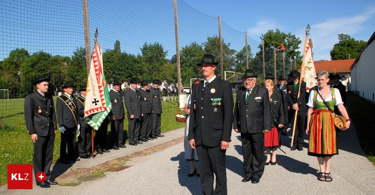 A group of uniformed individuals, possibly military or police, stand in line with flags. They wear hats, uniforms, and shoes. A woman in a white dress and black shoes stands in the center.