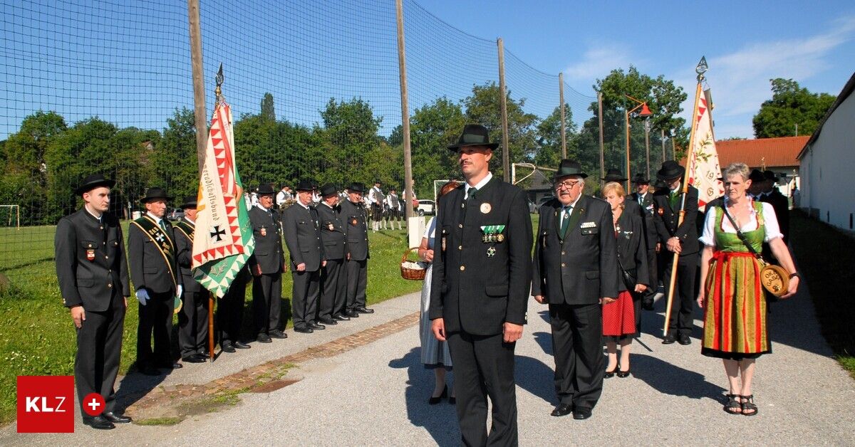A group of uniformed individuals, possibly military or police, stand in line with flags. They wear hats, uniforms, and shoes. A woman in a white dress and black shoes stands in the center.
