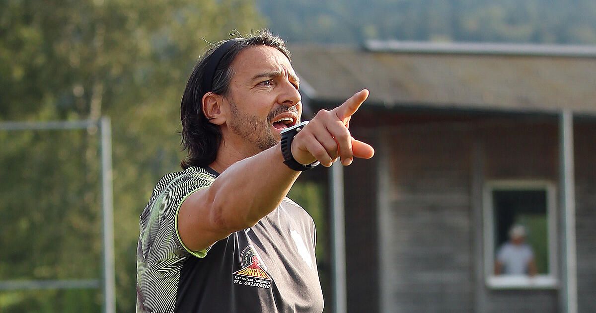 A man wearing a black and green striped shirt with a watch is pointing towards something with his mouth open.