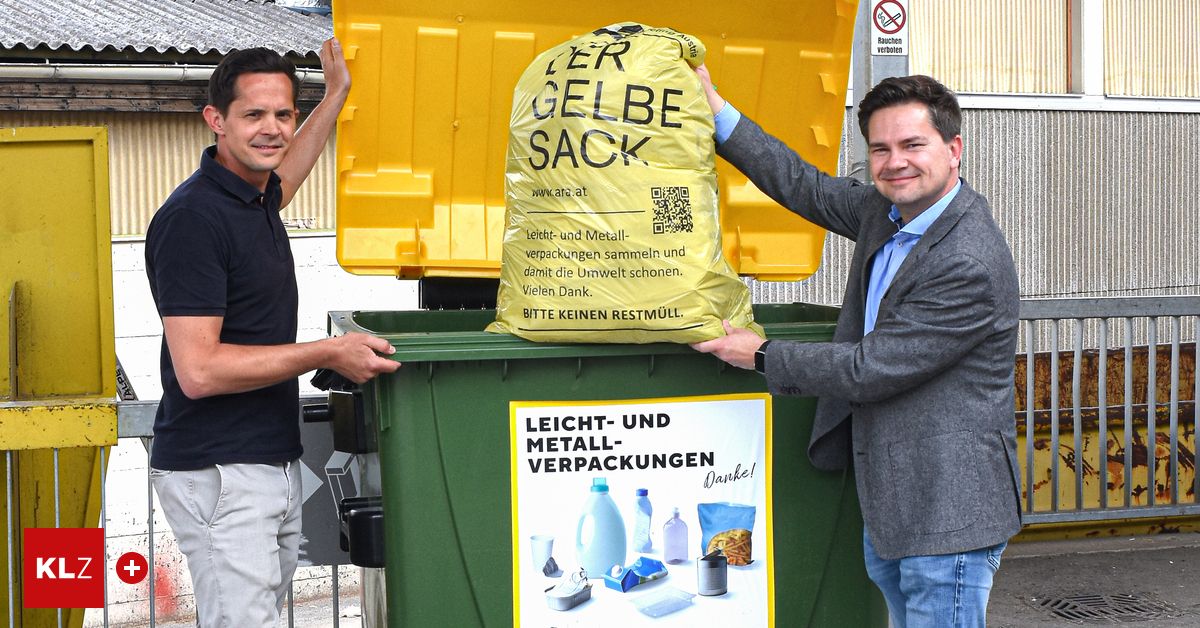 Zwei Männer lächeln und posieren für ein Foto mit einem gelben Recyclingsack und einem grünen Mülleimer.