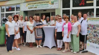 Eine Gruppe von Frauen feiert das 1-jährige Jubiläum der Schatzkiste in Preußisch Oldendorf. Sie stehen vor einem Geschäft.