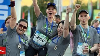 Eine Gruppe von Läufern mit Medaillen feiert bei einem Marathon. Eine Läuferin mit der Nummer 4022C lächelt mit erhobenen Armen.