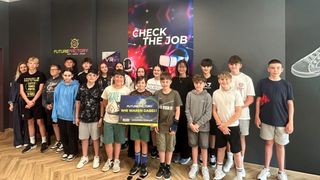 Gruppenfoto von jungen Leuten, die vor einem Banner, das Check the Job sagt, für die Kamera posieren. Der Junge in der Mitte hält ein Schild, auf dem FutureFactory wir waren dabei steht.
