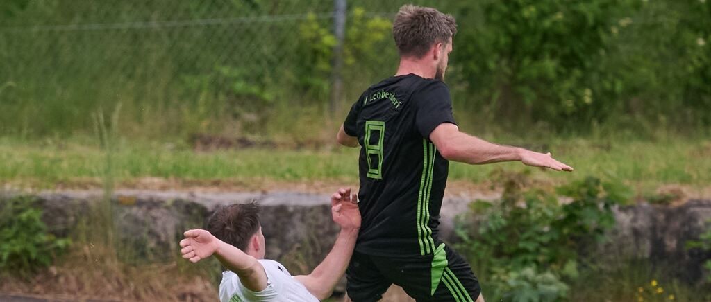 Zwei Fußballspieler, einer in Schwarz und einer in Weiß, sind in einem Spiel engagiert. Der Spieler in Schwarz hat die Nummer 8 auf seinem Trikot.