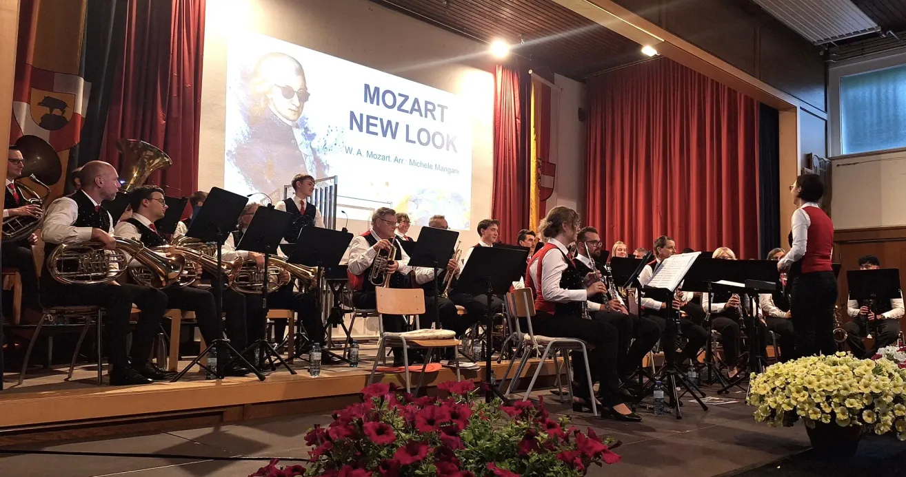 Eine Band spielt auf der Bühne Instrumente mit einer großen Leinwand im Hintergrund, auf der Mozart New Look steht.