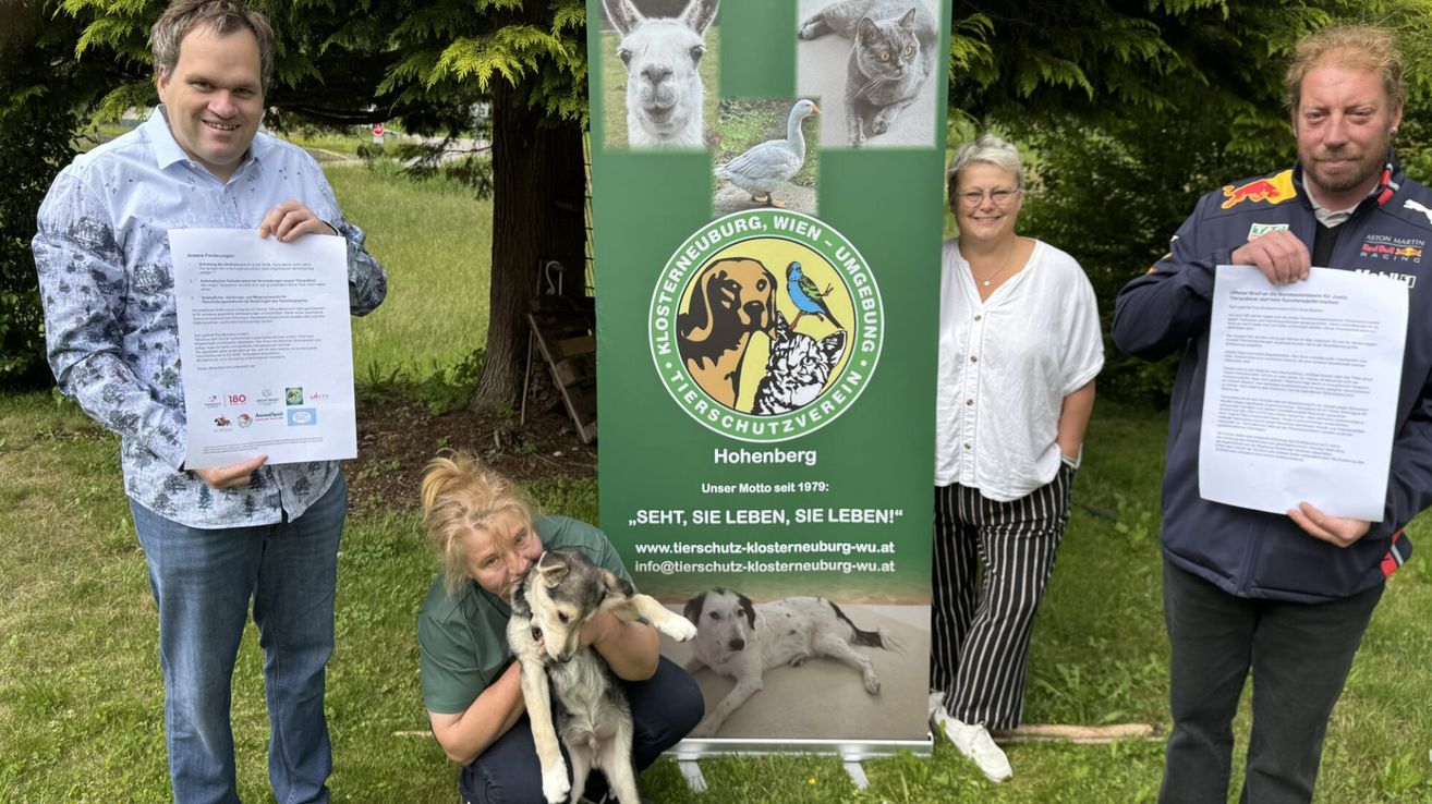 Zwei Frauen und eine Frau, die einen Hund hält, stehen neben einem Poster mit Tierbildern. Das Poster sagt: 'Klosterneuburg, Wien - Tierschutzverein Hohenberg.'