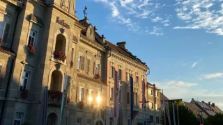 Ein Gebäude mit dem Wort Raffaun und einem Turm ist bei Sonnenuntergang zu sehen. Es gibt Flaggen und ein Schild, das Sparkasse der Stadt Leibnitz liest.