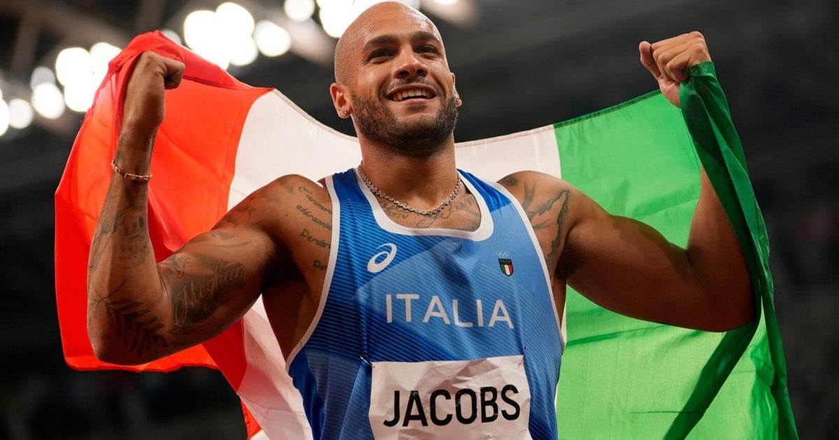 An athlete wearing a blue sports jersey with the word 'Italia' and 'Jacobs' celebrates with a flag in the background.