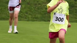 Ein kleines Mädchen läuft in einem Rennen mit der Nummer 300 auf ihrem Shirt. Hinter ihr läuft eine erwachsene Frau mit einer Nummer auf ihren Shorts.