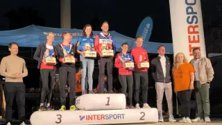 Sieger eines Sportevents posieren mit Trophäen auf einem Podest für ein Foto.