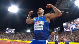 Ein Athlet feiert den Sieg beim Event München 2022, trägt ein blaues Trikot mit 'SPAR' und 'JACOBS', vor einem jubelnden Publikum.