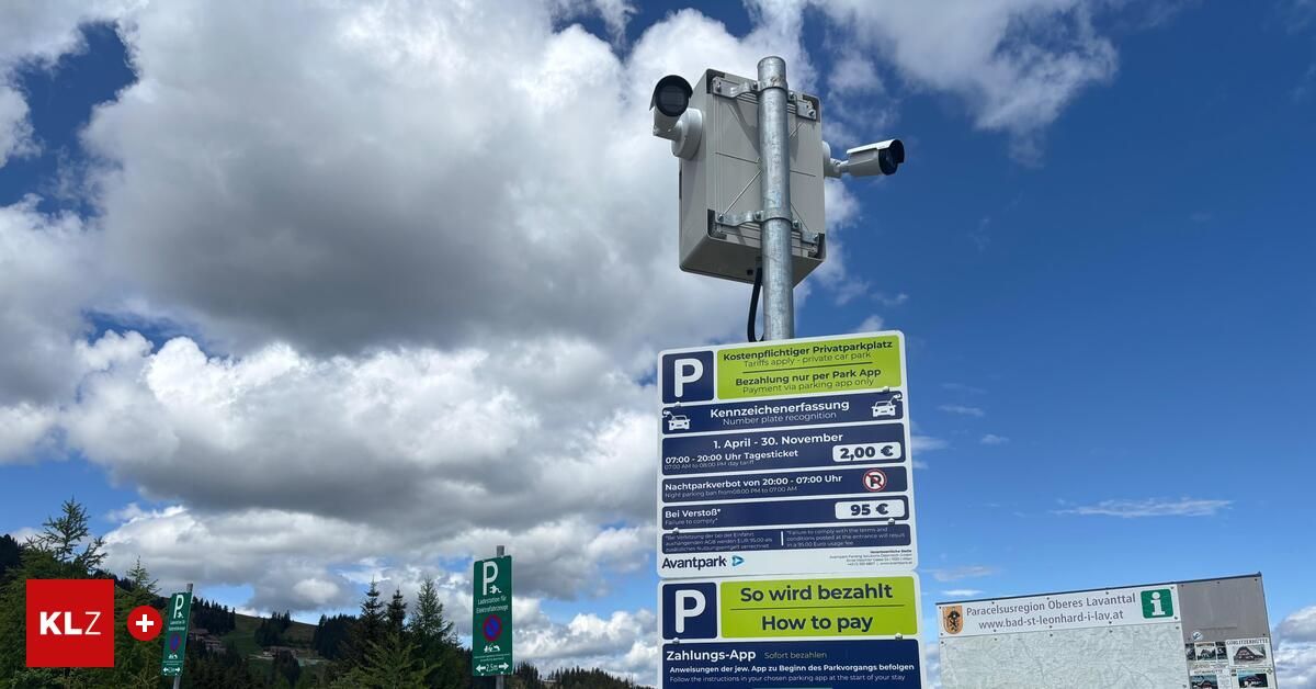 Ein Pfosten mit Überwachungskameras, ein blaues Schild mit 'Parken', 'Wie wird bezahlt' und einem QR-Code. Darunter ein gelbes Schild mit Parkdetails und Gebühren. Der Himmel ist bewölkt.