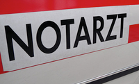 Ein Schild zeigt das Wort 'Notarzt' in fetten schwarzen Buchstaben auf weißem Hintergrund, was wahrscheinlich einen Rettungsdienst anzeigt.