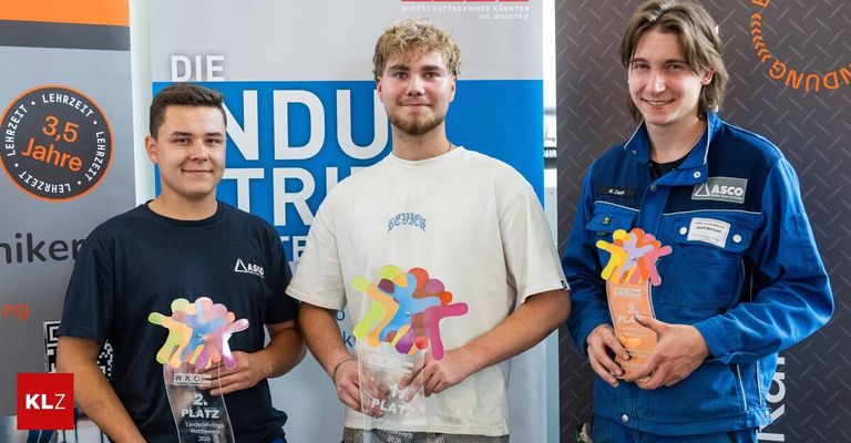 Drei Männer stehen nebeneinander und halten Trophäen. Der Mann auf der linken Seite hält eine Trophäe mit den Texten '2. Platz' und 'Landessieger Landeswettbewerb 2026'. Der Mann in der Mitte hält eine Trophäe mit dem Text '1. Platz'. Der Mann auf der rechten Seite hält eine Trophäe mit dem Text '3. Platz'. Sie stehen vor einem Banner mit der Aufschrift 'DIE INDUSTRIE'.