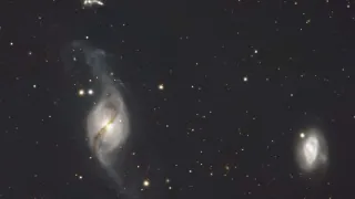 Ein Tiefraumbild zeigt mehrere Galaxien mit einer Spiralstruktur, verstreute Sterne und einen dunklen Hintergrund.