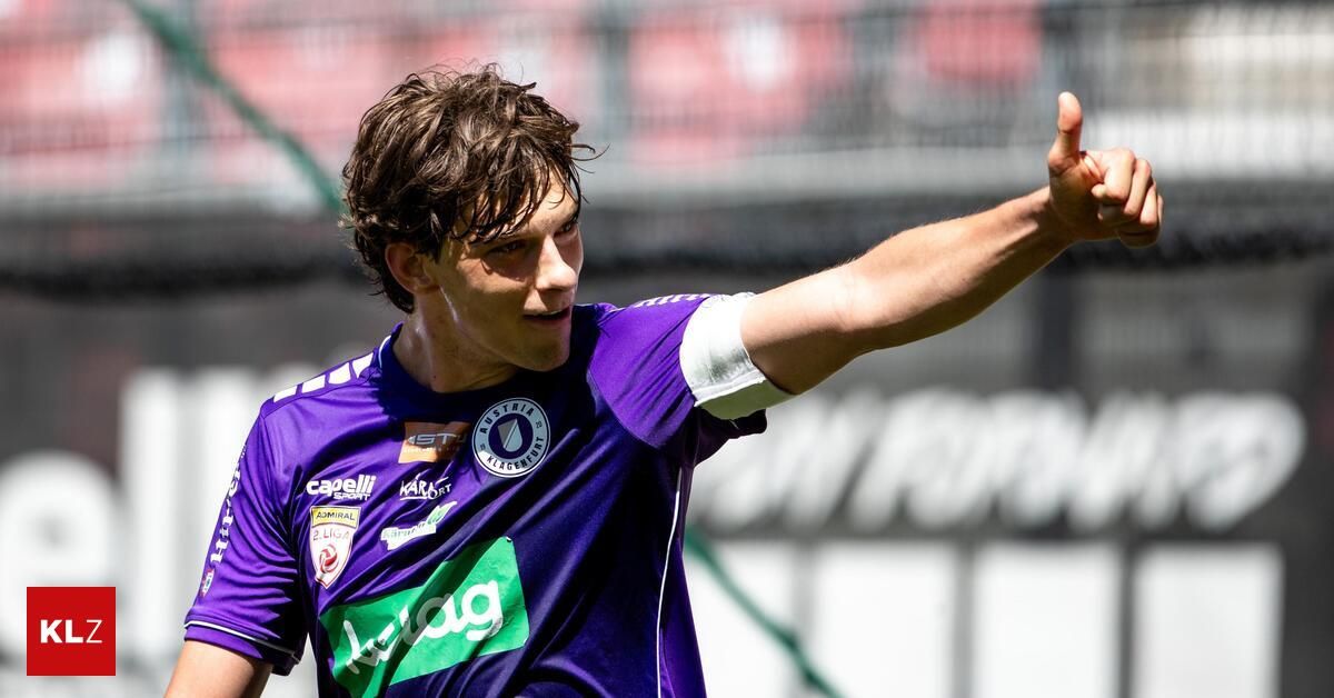 Ein Fußballspieler in einem lila Trikot winkt dem Publikum zu. Das Trikot hat verschiedene Logos und die Nummer 2 Liga.