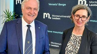 Zwei Personen stehen lächelnd vor einem Montanuniversitat Leoben-Schild, der Mann im Anzug und die Frau mit Brille.
