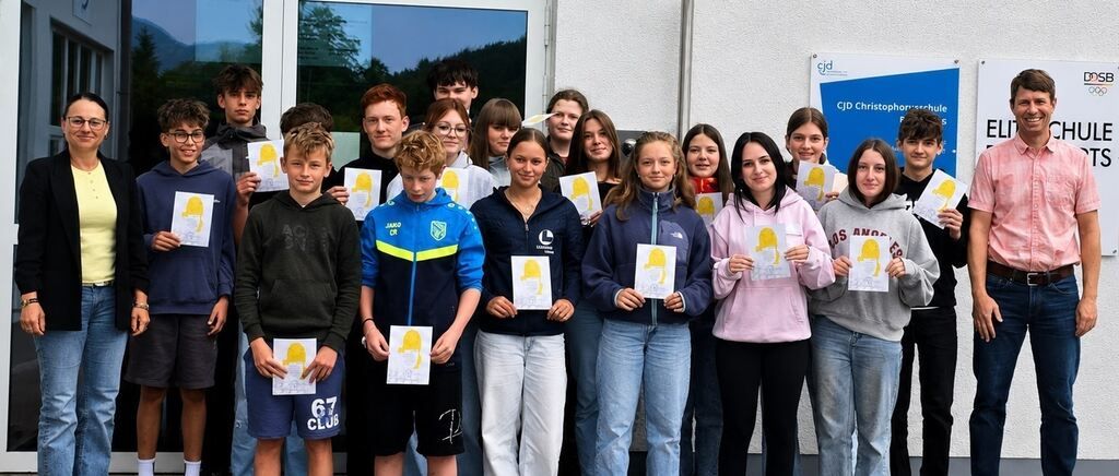 A group of young individuals posing for a photo outside a building with a sign reading CJD Christophorusschule.