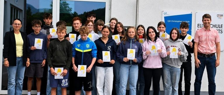 A group of young individuals posing for a photo outside a building with a sign reading CJD Christophorusschule.