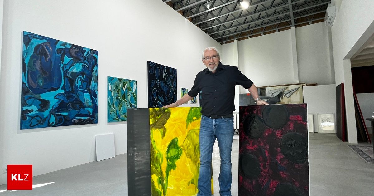 Ein älterer Mann steht in einer Kunstgalerie mit mehreren abstrakten Gemälden hinter ihm, eines davon ist gelb und grün.