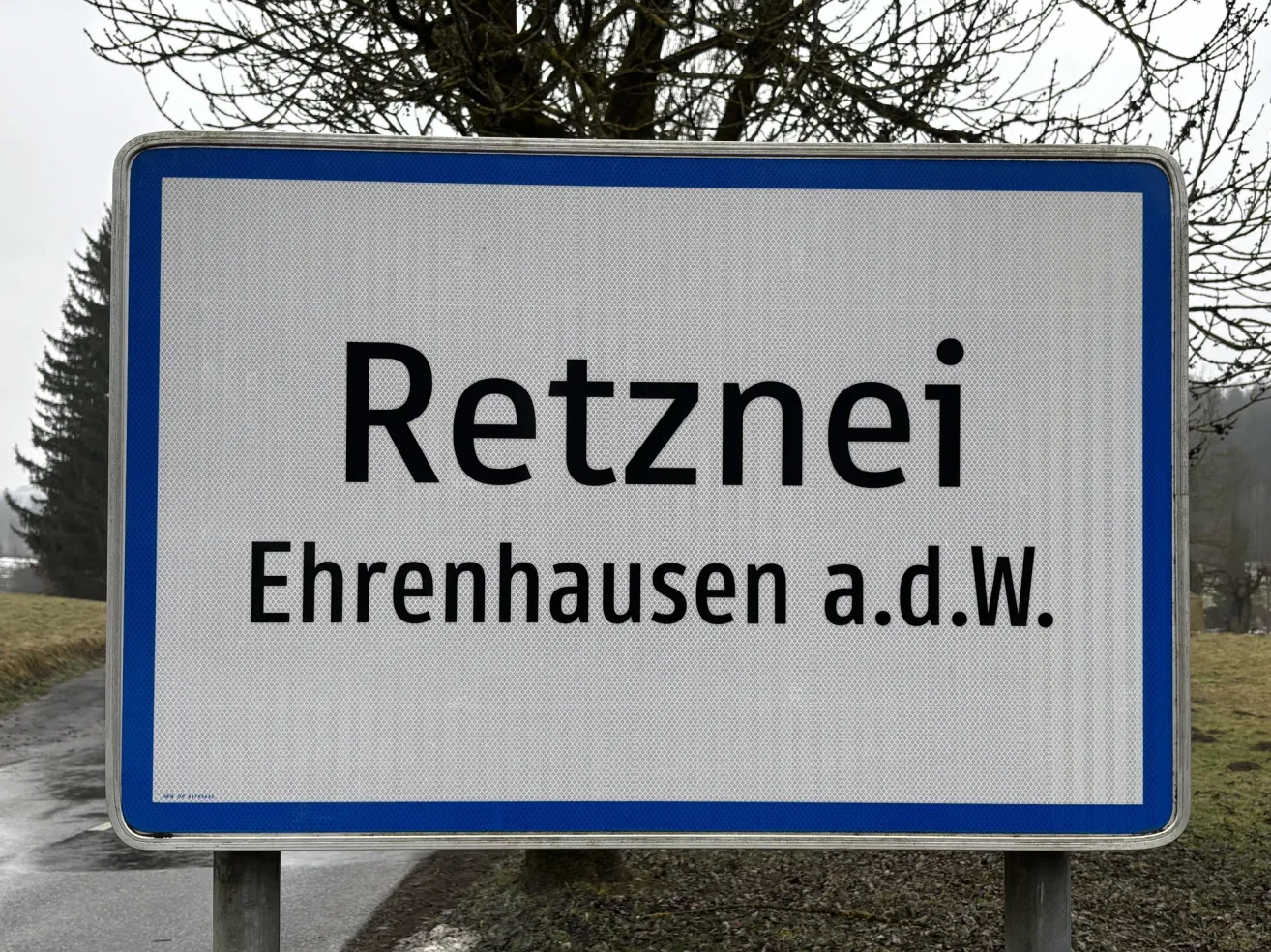 Ein weißes Schild mit blauen Rändern zeigt den schwarzen Text 'Retznei Ehrenhausen a.d.W.'.