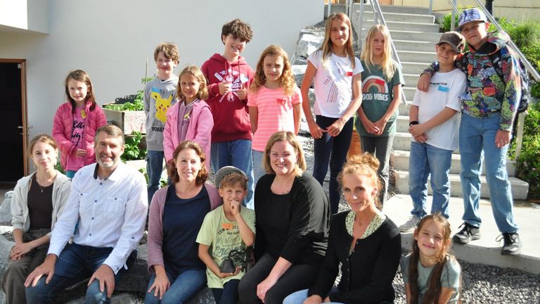 A group of people, including children and adults, are posing for a photo on a rocky surface, with a woman holding a boy on her lap.
