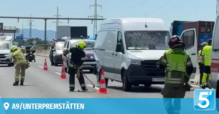 Ein Mann in einem gelben Helm reinigt die Straße mit einem Besen. Ein weißer Van ist hinter ihm geparkt. Rechts steht eine Person in einem grünen Weste.