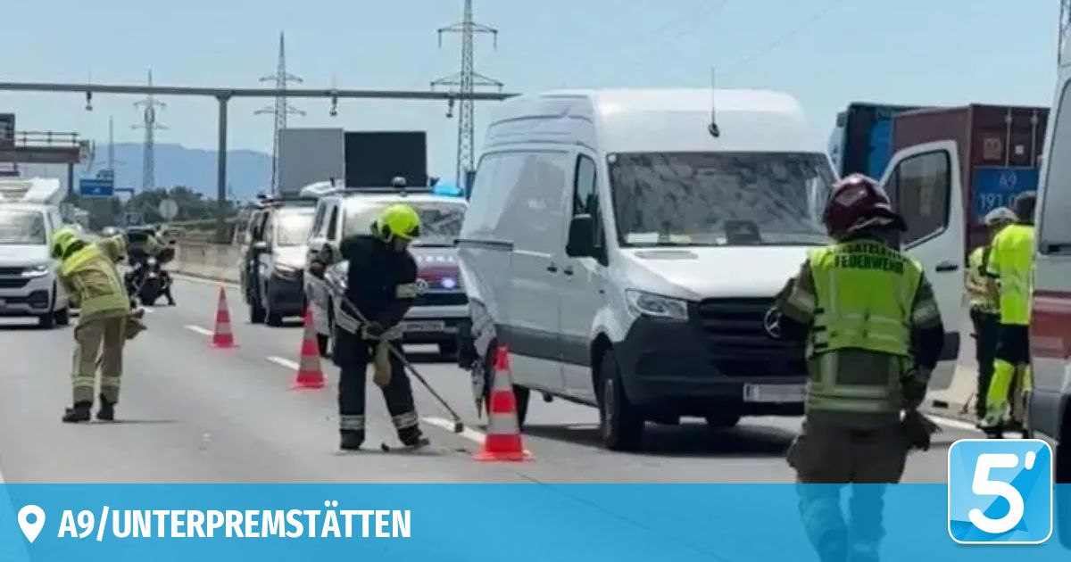 Ein Mann in einem gelben Helm reinigt die Straße mit einem Besen. Ein weißer Van ist hinter ihm geparkt. Rechts steht eine Person in einem grünen Weste.
