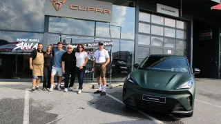 Eine Gruppe von Menschen steht vor einem CUPRA-Händler und posiert neben einem grünen CUPRA RAVAL-Auto. Das Schild des Händlers hat ein Logo und Text.