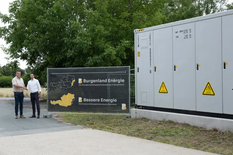 Ein Schild für Burgenland Energie steht neben einem Generator. Ein gelbes Dreieck mit Ausrufezeichen befindet sich am Generator.