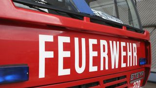 Nahaufnahme eines roten Feuerwehrwagens mit dem Wort 'FEUERWEHR' in Weiß geschrieben.