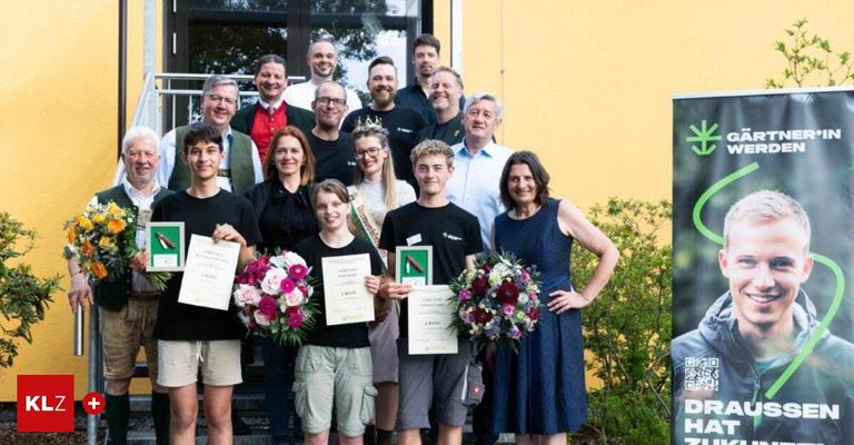 Eine Gruppe von Menschen steht vor einem Gebäude mit Blumen und Urkunden. Sie lächeln und halten Urkunden in den Händen. Sie feiern wahrscheinlich eine Leistung.