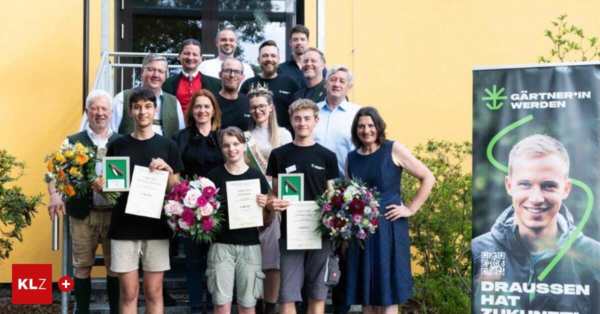 Eine Gruppe von Menschen steht vor einem Gebäude mit Blumen und Urkunden. Sie lächeln und halten Urkunden in den Händen. Sie feiern wahrscheinlich eine Leistung.