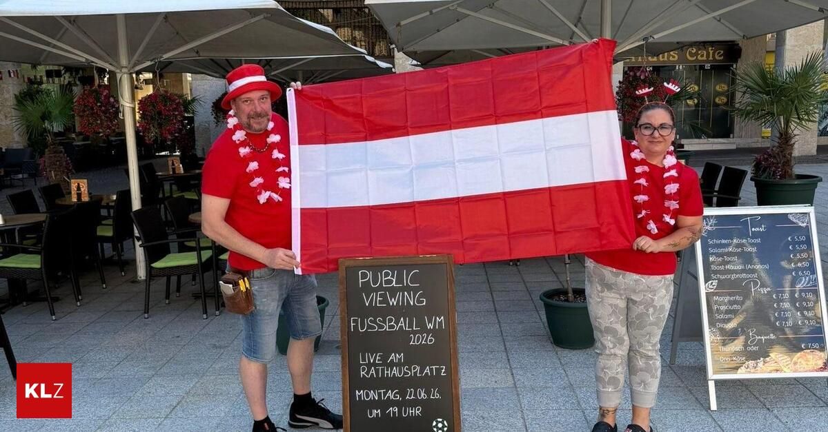 Ein Mann und eine Frau stehen draußen und halten eine große österreichische Flagge. Sie stehen neben einem Schild für eine öffentliche Fußball-Match-Ansicht am Rathausplatz am Montag, den 26. Juni um 19:00 Uhr.