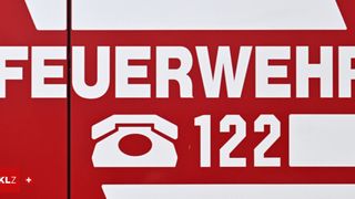 Rotes Schild mit weißem Text und Symbol, das 'FEURWEHR 122' liest. Das Symbol ist ein Telefonhörer.