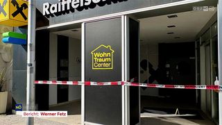 Der Eingang zu einem Gebäude mit einer geschlossenen Tür, einem gelben und schwarzen Schild mit der Aufschrift Wohn Traum Center und rotem und weißem Polizeiband.